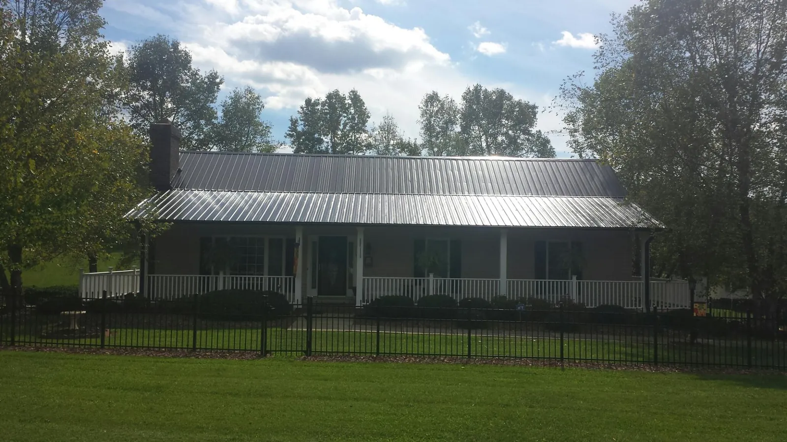Gray metal roof on a brick ranch with a full width front porch — Gutter Guard Installation work by our crew in Carey