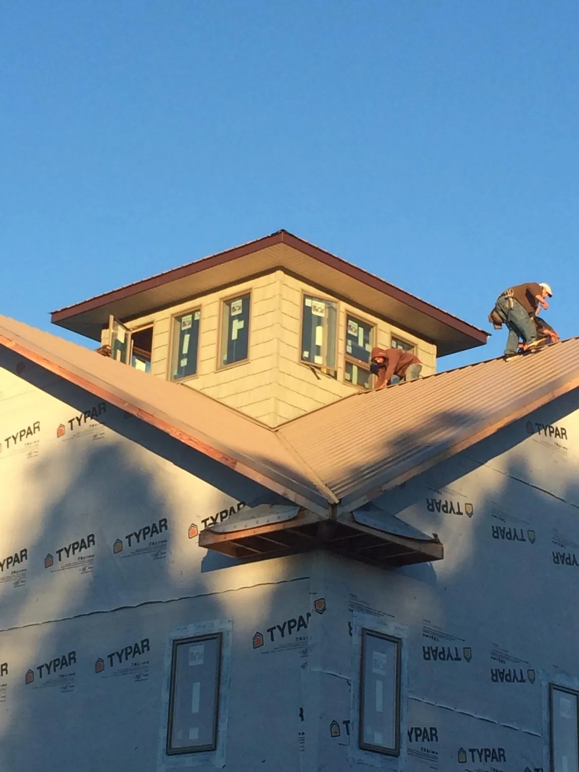Roofers working around a rooftop cupola on a new metal roof at sunset — Roof Waterproofing in Carey by Roofing Brothers